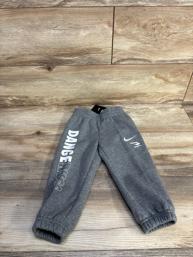 Flat lay of grey toddler Nike joggers (2T) showing white DANGER text, Nike swoosh, elastic waistband and cuffs on wood floor
