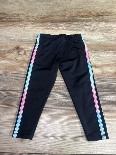 Front view of Adidas active leggings in black, size 2T, showcasing pink and blue side stripes on a wood background