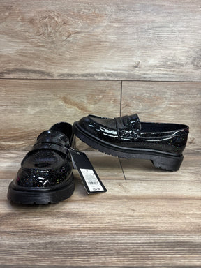 Black glittery kids' loafers with chunky soles and price tag on wood background