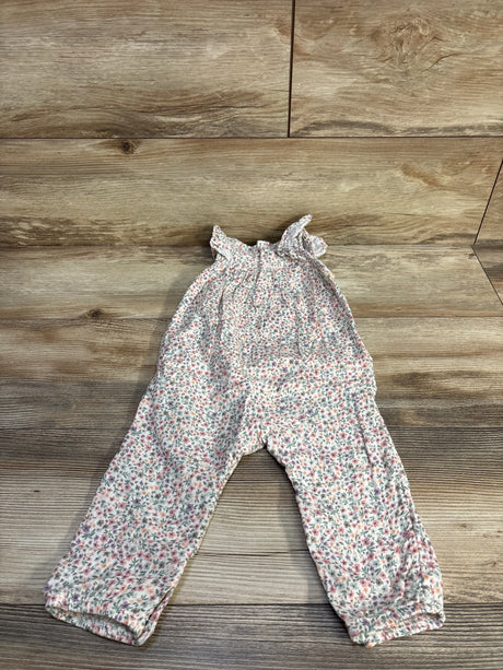 Flat lay of white smocked floral baby jumpsuit 12 months showing ruffled straps and elastic cuffs on wood background