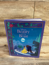 Front view of Disney Beauty and the Beast hardcover showing cover with Belle in yellow gown and Beast, purple cover on wood