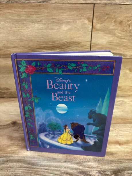 Front view of Disney Beauty and the Beast hardcover showing cover with Belle in yellow gown and Beast, purple cover on wood
