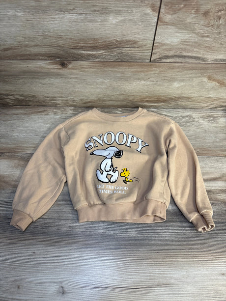 Tan kids Snoopy sweatshirt with Woodstock, cartoon print, long sleeves, laid on wood floor