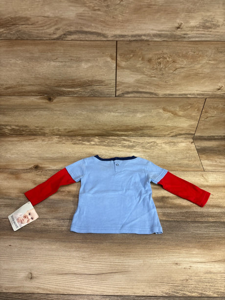 Buster Brown light blue baby shirt with red layered sleeves on a wood background
