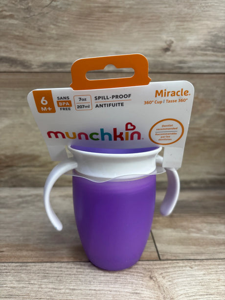 Front view of packaged Munchkin Miracle 360 Trainer Cup showcasing purple 7-ounce cup and white handles on wood background