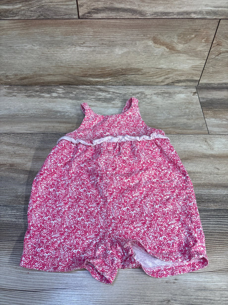 Flat lay of pink floral tank romper showing ruffle waist trim and sleeveless straps on wood floor
