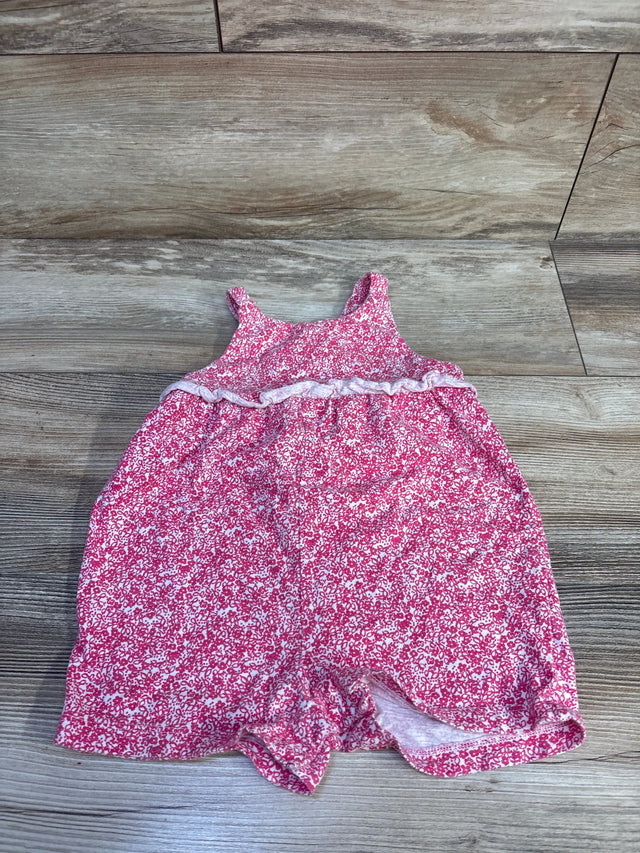 Flat lay of pink floral tank romper showing ruffle waist trim and sleeveless straps on wood floor
