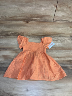Peach short sleeve baby dress with ruffled sleeves, smocked bodice, and subtle gold shimmer