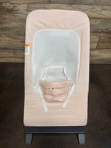 Top-down view of Baby Delight Alpine Deluxe bouncer in light pink showing white mesh seat insert, safety straps, and black base on wood floor