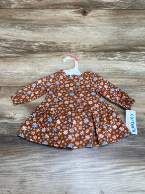 Front view of newborn rust-brown floral long-sleeve dress on hanger showing gathered skirt on wood background