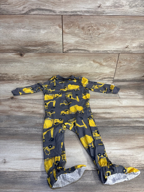 Top-down view of grey footed sleeper 18mo with yellow truck print and grip soles on wood background