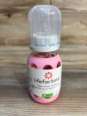 Lifefactory glass baby bottle with pink silicone sleeve and BPA-free cap on wood background