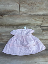 Front flat lay of OshKosh baby dress showcasing pink Swiss dot fabric and floral eyelet lace trim with wood plank background