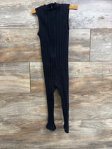 Front view of black ribbed toddler jumpsuit with footed legs on wooden hanger against wood plank background