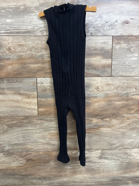 Front view of black ribbed toddler jumpsuit with footed legs on wooden hanger against wood plank background