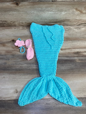 Flat lay of blue crochet mermaid tail with textured fin and ruffle waist and two pink crocheted headbands with pearls on wood