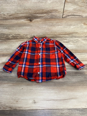Front view of toddler red and navy plaid button-up shirt showcasing long sleeves, chest pocket, and white buttons on light wood background