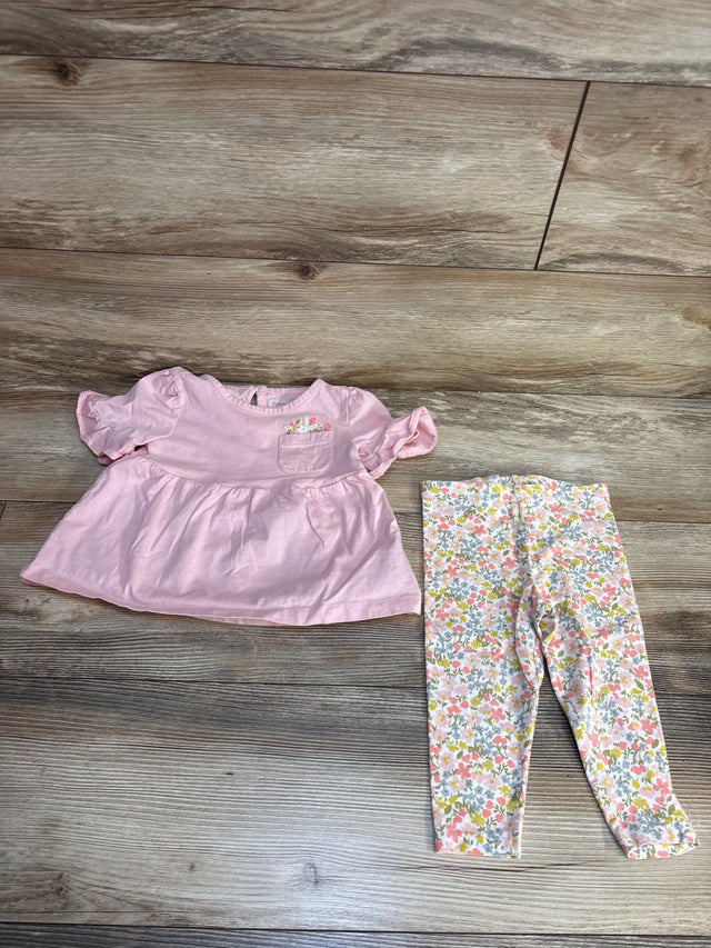 Pink baby top with floral pocket and matching floral leggings on wood floor