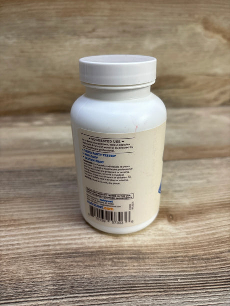 Rear view of NutriCost Colostrum 120 ct bottle showing suggested use text and barcode on beige label on wood surface