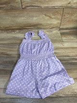 Flat-lay of purple Picapino polka-dot romper showing ruffled straps and smocked waist on wood floor