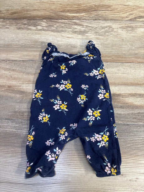 Flat-lay of navy floral sleeveless newborn jumpsuit showing ruffled shoulder straps and snap crotch on wood background