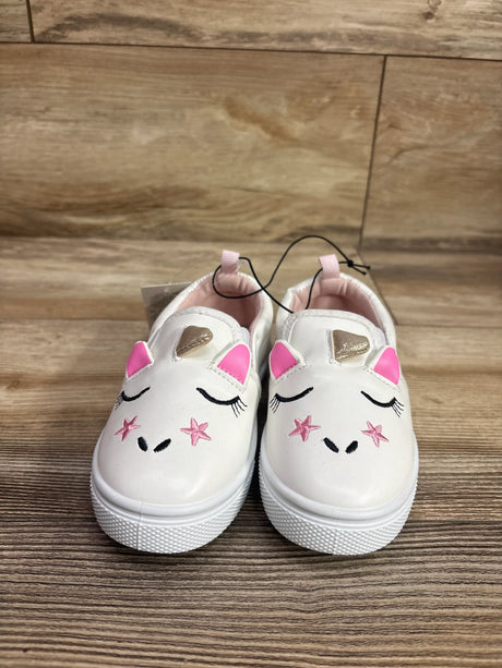 Front view of white Bocca slip-on unicorn sneakers showcasing pink ears, gold horns, and embroidered faces on wood flooring