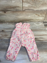 Flat lay of pink Cat and Jack gauze jumpsuit with collared top, ruffle straps, floral print and elasticized ankles on wood background