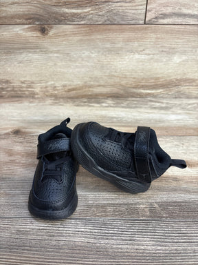 Pair of black toddler sneakers with Velcro straps on wooden floor background