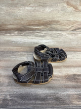 Side view of Children's Place leather fisherman sandals in dark brown with white stitching and hook and loop strap on wood plank floor