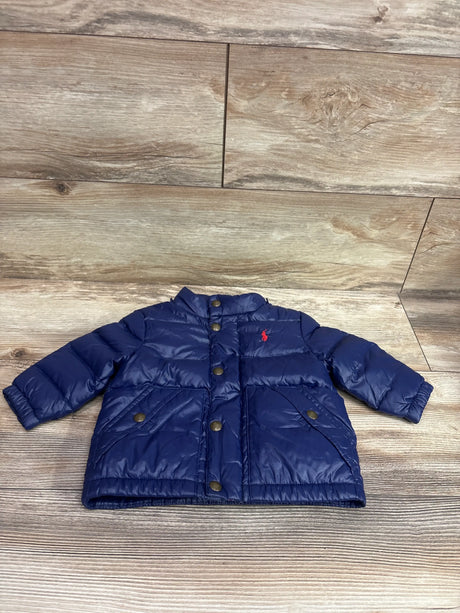 Front view of navy Ralph Lauren puffer jacket, size 9 months, with quilted panels, snap buttons, and pockets on a wood floor