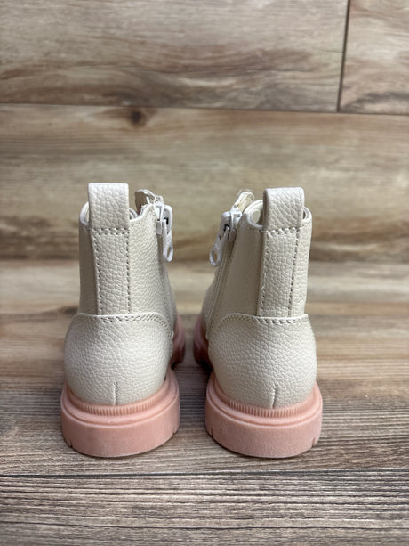 Pair of cream-colored children's boots with pink soles on wood floor background