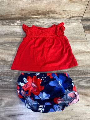 Flat lay of Carter's 2-piece red eyelet top and navy floral bloomers showing eyelet yoke and flutter sleeves with elastic waist on light wood background
