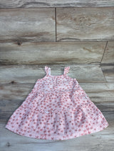 Flat lay of Rabbit + Bear pink floral tiered toddler dress showing ruffled tiers and ruffled shoulder straps on light wood floor