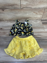 Flat lay of Little Lass 2-piece lemon-print gem top and yellow lace ruffle shorts on wood background