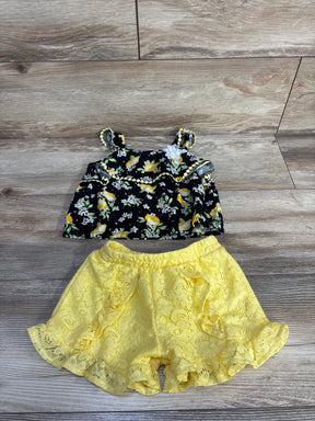 Flat lay of Little Lass 2-piece lemon-print gem top and yellow lace ruffle shorts on wood background