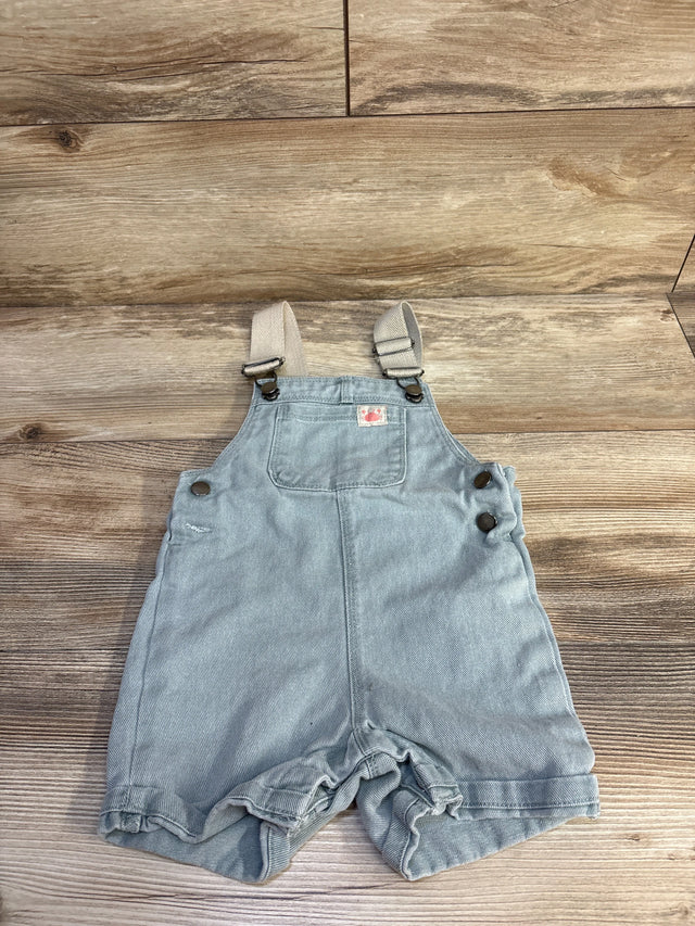 Top-down view of blue toddler denim shortalls (18M) with adjustable straps and side metal buttons on wood floor