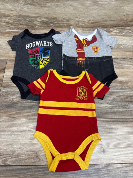 Front view of three Harry Potter bodysuits featuring Hogwarts and Gryffindor designs on a wood-grain background