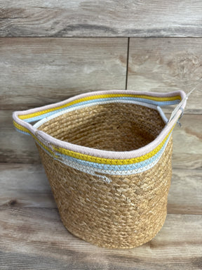 Top-front view of natural woven round storage bin with yellow and blue rim and braided texture on wood background
