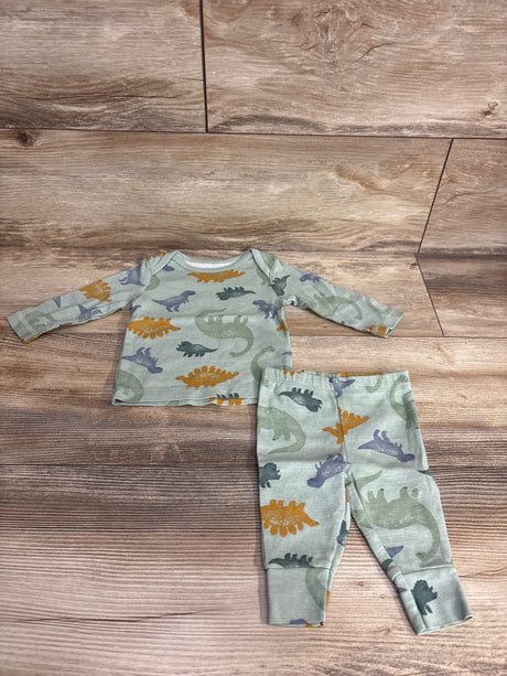 Baby pajamas set with colorful dinosaur prints on long-sleeve shirt and pants on wooden floor