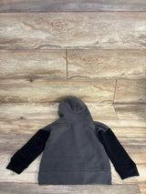 Gray kids hoodie with black sleeves laid flat on wood floor, cozy children's clothing