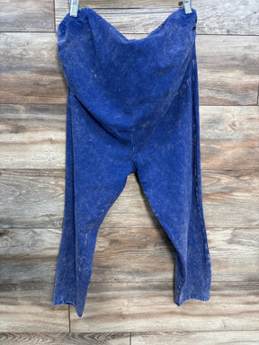 Blue acid-wash style hooded sweatpants hanging on clips against wooden wall background