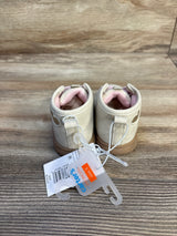 Pair of beige Carter's baby shoes with pink lining, size 3, on wood background