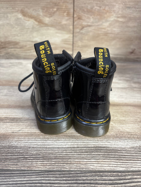 Rear view of Dr. Martens 1460 boots in black, size 4C, showcasing yellow stitching and pull tabs on a wood floor