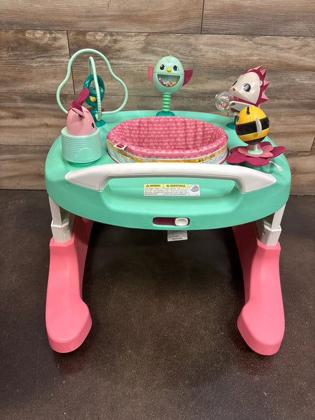 Front view of Tiny Love 4-in-1 Here I Grow Activity Center in Tiny Princess showcasing attached toys against wood backdrop