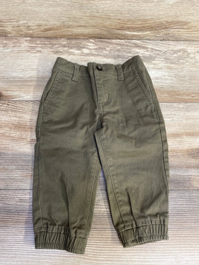Olive green toddler pants with elastic cuffs on wooden background