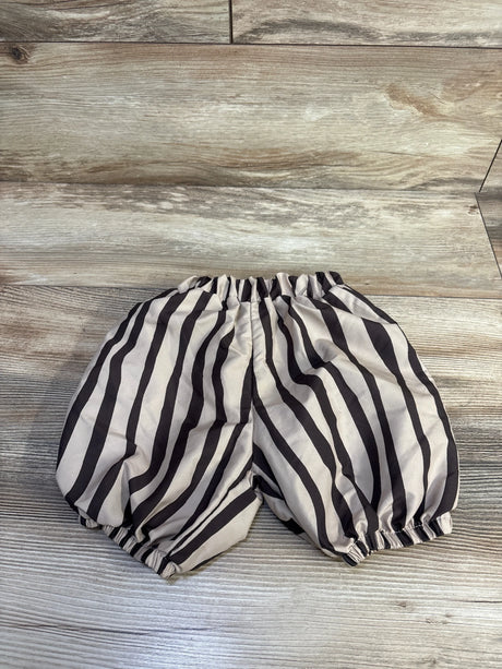 Top-down view of baby balloon pants with brown and black stripes, elastic waist and leg openings on wood background