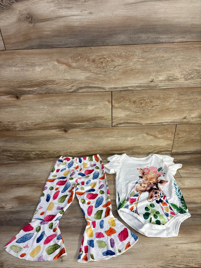 Flat lay of 2-piece baby set 18-24 mo: white bodysuit with giraffe graphic and colorful flared ruffle pants on wood floor