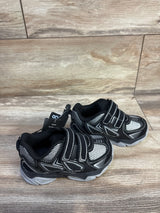 Angled view of Athletic Works toddler two-strap sneakers, black, mesh upper, reflective trim, gray sole on wood floor