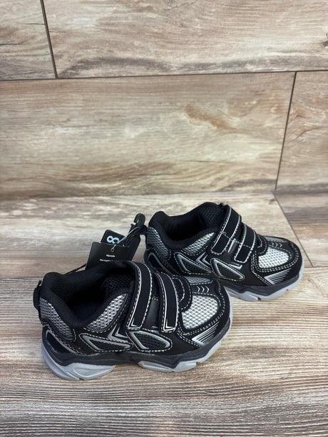 Angled view of Athletic Works toddler two-strap sneakers, black, mesh upper, reflective trim, gray sole on wood floor