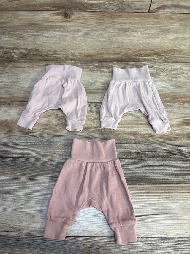 Soft baby harem pants in pink and white, cozy newborn clothing on wood floor